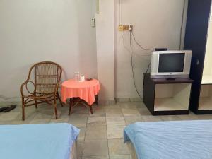 a room with a table and a tv and a chair at OYO 90885 Bera Pentagon Inn in Kampong Kerayong