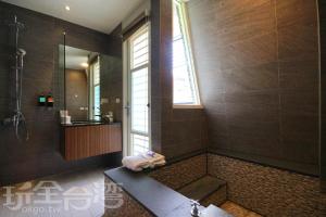a bathroom with a shower and a tub with a window at 礁溪玥湯溫泉旅店 in Jiaoxi