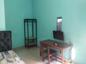 a room with a desk and a bed and a mirror at OYO 93306 Rinjani Guest House in Balikpapan