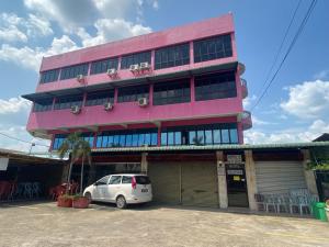 a pink building with a car parked in front of it at OYO 90885 Bera Pentagon Inn in Kampong Kerayong