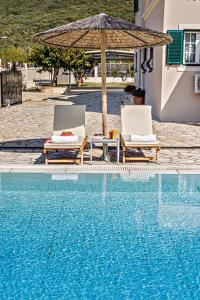 two chairs and an umbrella next to a swimming pool at Skidi Beach house in Ágios Matthaíos