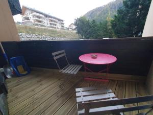 une table rose et une chaise sur un balcon dans l'établissement Chamonix / Argentière - Duplex 6p, à Chamonix-Mont-Blanc