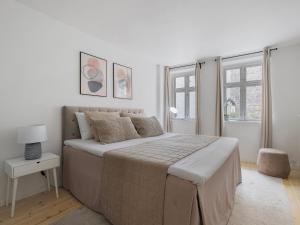 a white bedroom with a large bed and windows at Sanders Main - Popular Two-Bedroom Duplex Apartment Next to Magical Nyhavn in Copenhagen