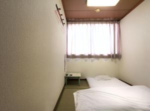 Hotel Wako في أوساكا: سريرين في غرفة صغيرة مع نافذة