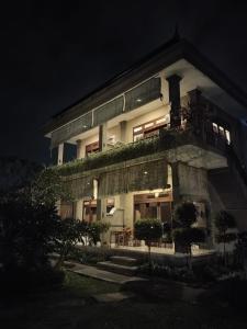 Putra Bisma Guesthouse في أوبود: مبنى كبير مع شرفة في الليل