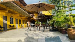 a patio with an umbrella and tables and chairs at Motel Seri Mutiara in Kuah +25 photos