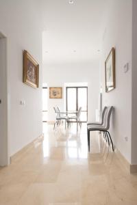 ein weißes Zimmer mit Stühlen und einem Tisch darin in der Unterkunft Apartamentos Casa-Palacio Santa Pola in Ronda
