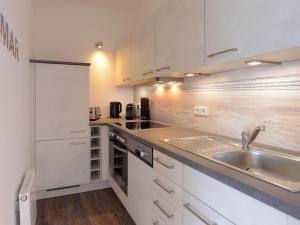 kuchnia z białymi szafkami i zlewem w obiekcie Ohlerich Speicher App_ 27 w mieście Wismar