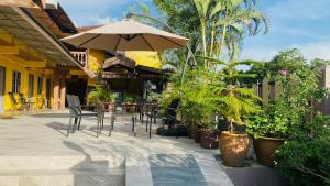 a patio with an umbrella and chairs and plants at Motel Seri Mutiara in Kuah