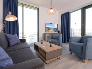 een woonkamer met een bank, 2 stoelen en een tv bij Ohlerich Speicher App_ 46 in Wismar