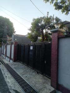 una valla con puertas negras y una pared de ladrillo en Kost eksklusif Gondang & Guest House, en Srondolwetan