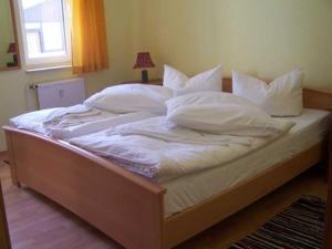 a large bed with white sheets and pillows at Anbau Waldhotel - Fewo Mellien in Göhren