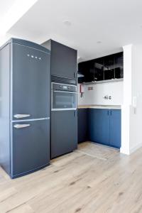 a kitchen with blue cabinets and a refrigerator at Sunny Beachfront Apt in Costa da Caparica in Almada