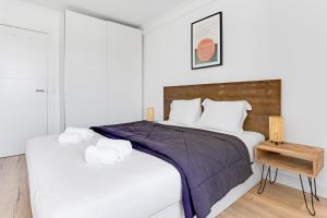 a white bedroom with a large bed and a table at Sunny Beachfront Apt in Costa da Caparica in Almada