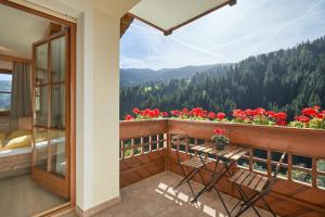 a balcony with a table and chairs and flowers at Jaufenspitze Blasighof in Racines