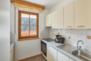 a white kitchen with a sink and a window at Jaufenspitze Blasighof in Racines