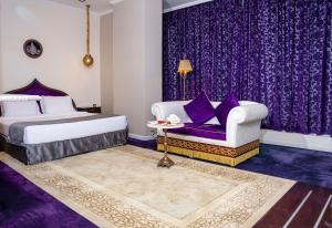 1 dormitorio con cortinas moradas, 1 cama y 1 sofá en Saraya Corniche Hotel, en Doha