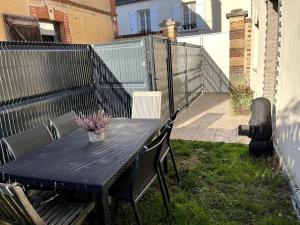 a blue table and chairs on a patio with a fence at Petite maison de charme à 10 minutes de Disney ! in Montévrain