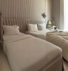 2 camas en una habitación de hotel con sábanas blancas en The Queen Airport Hotel en Arnavutköy