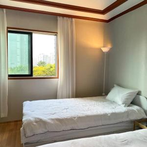 a bedroom with two beds and a window at Hue Stay in Ansan