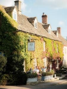 an ivy covered building with a sign on it at New Inn at Coln in Coln Saint Aldwyn