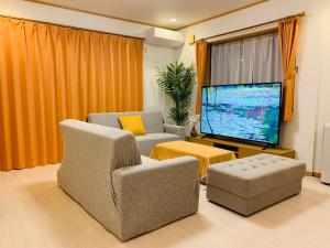 ein Wohnzimmer mit 2 Stühlen und einem Großbild-TV in der Unterkunft Kamei House in Tokio