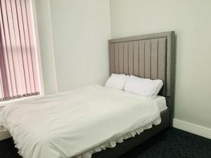 Una cama con sábanas blancas y almohadas en un dormitorio en Marina Apartments en Bradford