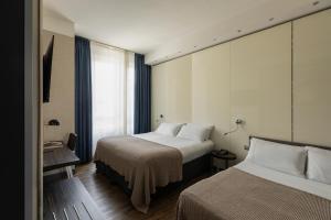 Habitación de hotel con 2 camas y ventana en c-hotels Atlantic en Milán