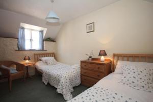 a bedroom with two beds and a dresser and a window at The Old House Cottages in Nether Stowey