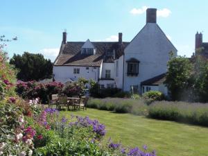 a large white house with a garden with flowers at The Old House Cottages in Nether Stowey