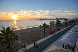 um grupo de pessoas caminhando na praia ao pôr do sol em Hotel Zanzi em Durrës