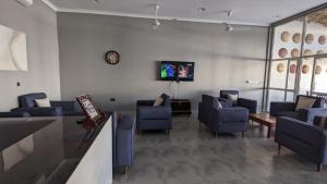 une salle d'attente avec des chaises bleues et une télévision à écran plat dans l'établissement Mafia Dream Hotel, à Kilindoni