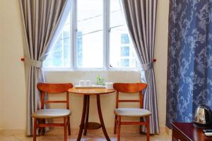 een tafel en 2 stoelen in een kamer met een raam bij Violet Star Hotel and Spa in Ho Chi Minh-stad