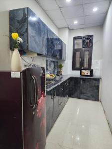 uma cozinha com armários pretos e um frigorífico preto em Homlee-Vintage 2BHK Apt Near Central Delhi em Nova Deli