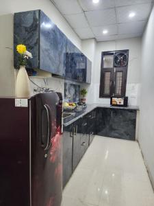 uma cozinha com armários pretos e um frigorífico preto em Homlee-Vintage 2BHK Apt Near Central Delhi em Nova Deli