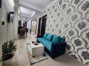 a living room with a blue couch and a wall at Homlee-Vintage 2BHK Apt Near Central Delhi in New Delhi