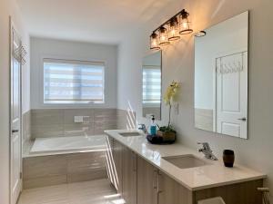 a bathroom with a tub and a sink and a mirror at 3 Bedroom Well-designed Townhouse in Whitby in Whitby +30 photos