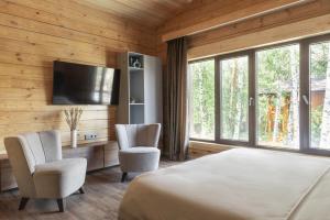 um quarto com uma cama e duas cadeiras e uma televisão em Villa - ваш загородный дом em Borovoye