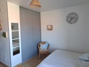 1 dormitorio con 1 cama y reloj en la pared en La mer, en Balaruc-les-Bains