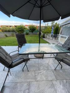 a glass table and chairs under an umbrella on a patio at Villa Joanne in Alexandroupoli