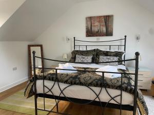 a bedroom with a black bed with pillows on it at Cottages at Woodlands, Appleloft in Wareham