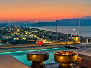 ein Glas Wein auf einem Tisch mit einem Teller Essen in der Unterkunft Alectrona Living Crete, Olīvea Luxury Apartment in Platanias