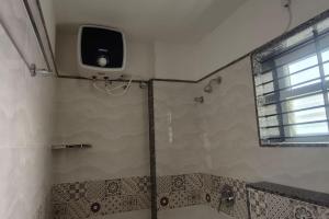 uma casa de banho com um chuveiro e uma televisão na parede em Compact yet beautiful 1bhk 402 em Bangalore