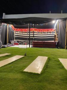 a stage with a green field and red chairs at شاليه اند هوم in Hail