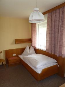ein kleines Schlafzimmer mit einem Bett und einem Fenster in der Unterkunft Pension Edelweiss in Sankt Martin am Tennengebirge