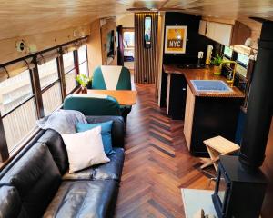 a living room with a couch and a kitchen in an rv at Skoolie Stays - Luxury American school bus conversion in Storrington