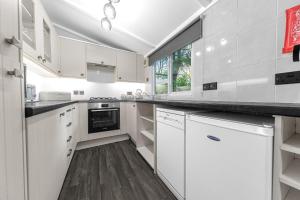 a kitchen with white cabinets and a wooden floor at Firgarth Lodge in Windermere