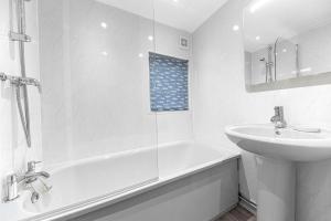 a white bathroom with a sink and a tub and a toilet at Firgarth Lodge in Windermere +26 photos