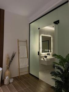 ein Badezimmer mit einer Glastür, einem Waschbecken und einem Spiegel in der Unterkunft شاليه اند هوم in Ha'il