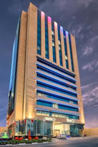 ein großes, hohes Gebäude mit blauen Fenstern auf einem Parkplatz in der Unterkunft Saraya Corniche Hotel in Doha